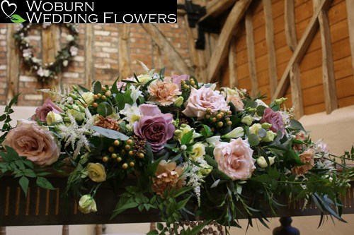 Ceremony flowers of Quicksand roses, lisianthus, astilbe, hypericum, freesia, trails of jasmine and mixed greenery.