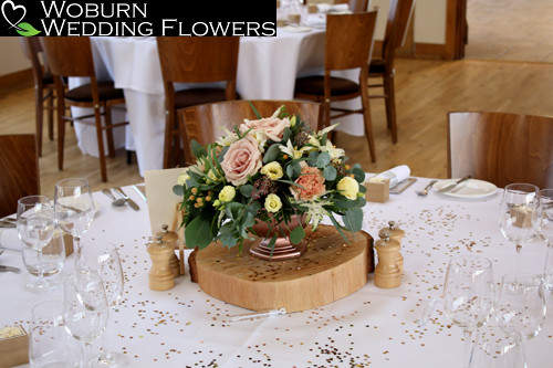 Rose gold urn of quicksand roses, hypericum,carnations, lisianthus and berried eucalyptus.