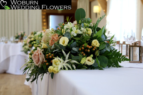 Top table arrangement containing Mixed  garden roses, asilbe, hypericum and berried eucalyptus.